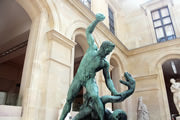 Escultura de bronze de homem lutando com serpente.